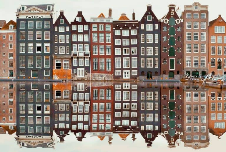 Amsterdam buildings reflected on a canal.